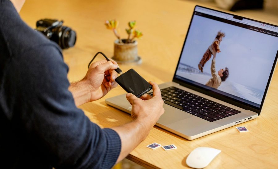A man sitting at a table with a laptop and cell phone